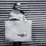 Smiling woman standing, holding a painting