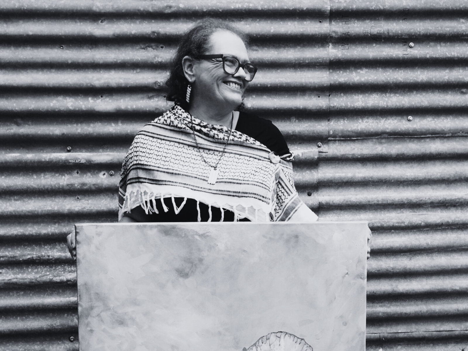Smiling woman standing, holding a painting 